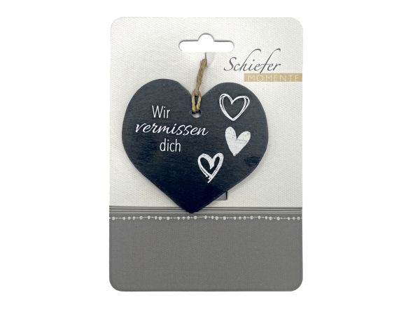 Herzanhänger aus schwarzem Schiefer mit weißer Aufschrift "Wir vermissen dich" sowie drei Herzen daneben.